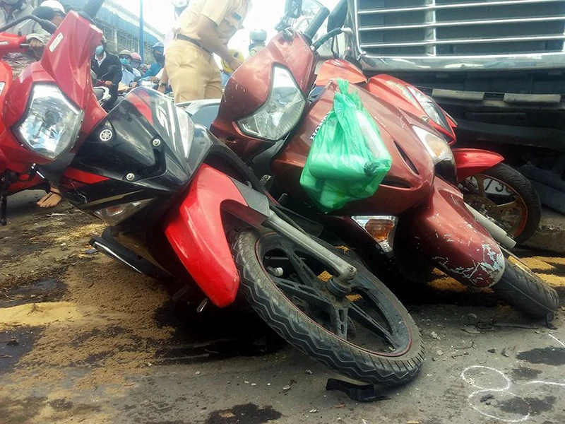 Ba xe máy bị hư hỏng nặng, nằm mắc kẹt trước đầu xe container 